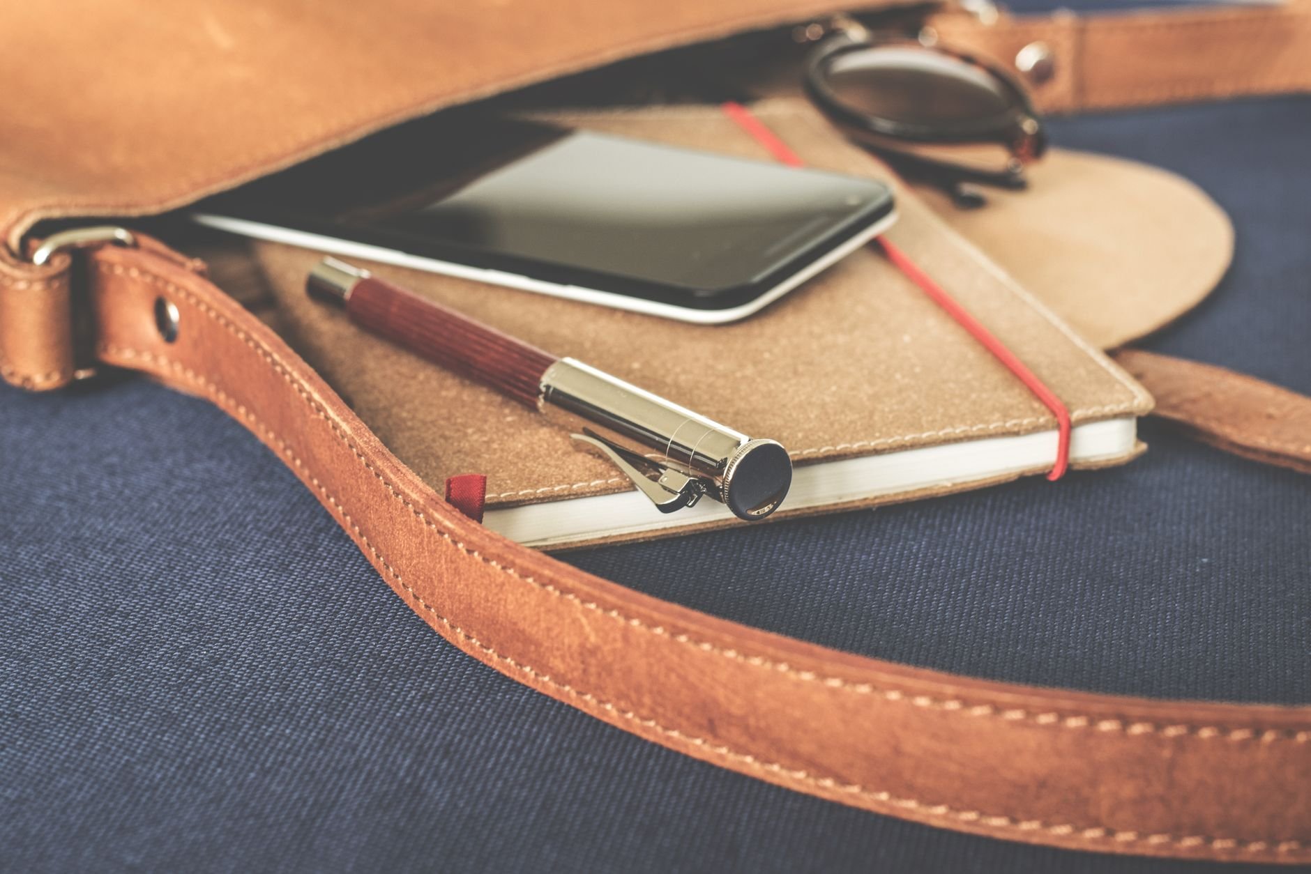 Fountain pen resting on a leather journal beside a smartphone, warm editorial light
